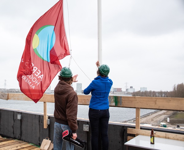 Het hijsen van de vlag op het dak van de nieuwbouw
